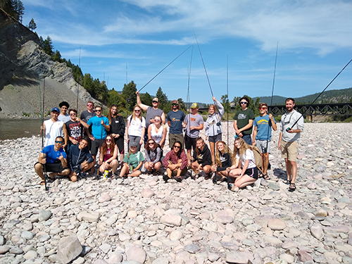 Incoming students pose for a photo along the river during a fishing trip