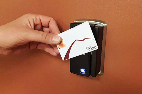  A student holds their Griz Card up to a card reader to gain access to a room in the library.