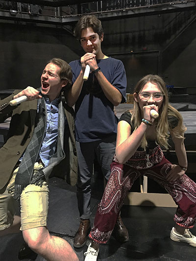 Three UM theater students sing into microphones during a rehearsal 