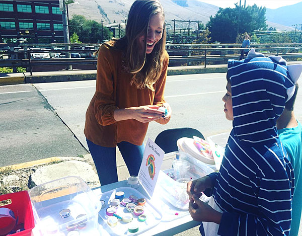 Natalie Temple hands out stickers to children as she staffs a table on Higgins Avenue Bridge. 
