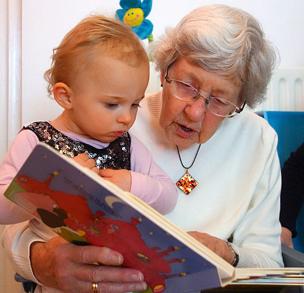 An older woman reads to a baby.