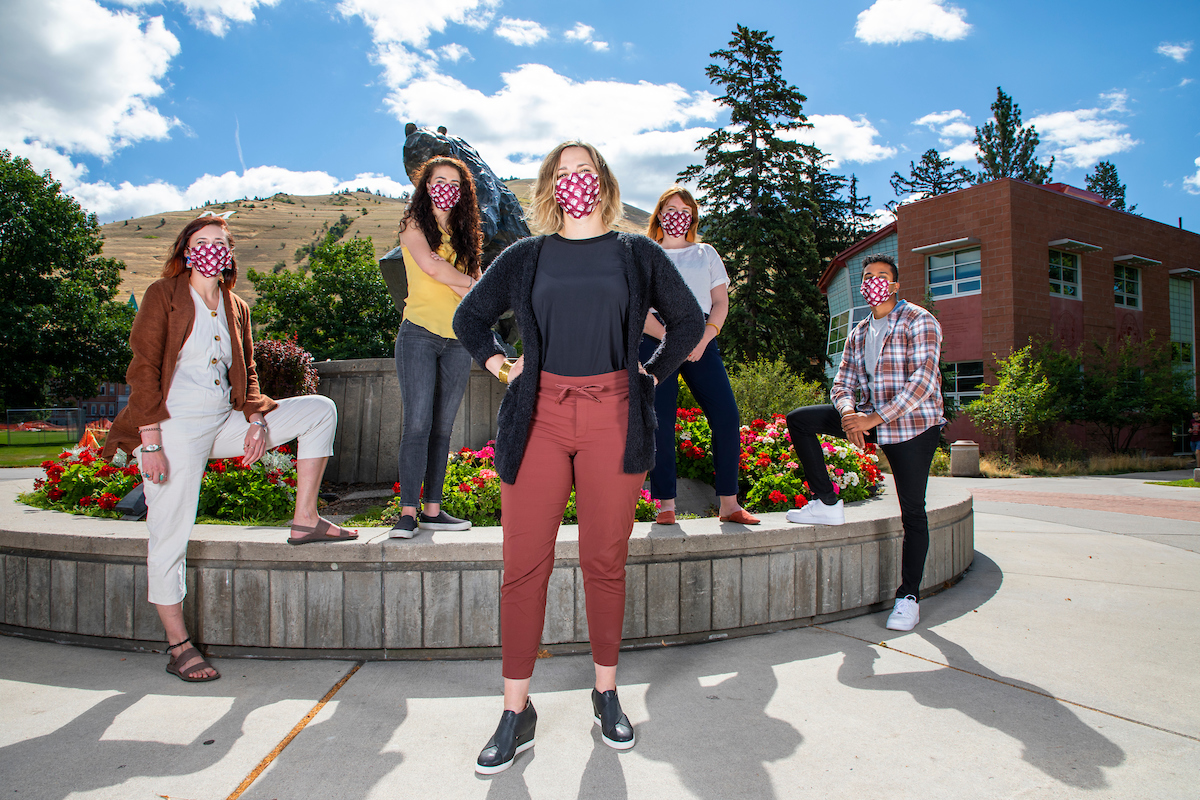 Five people stand in front of the Grizzly Bear statue in masks and the closest person has her hands on her hips 