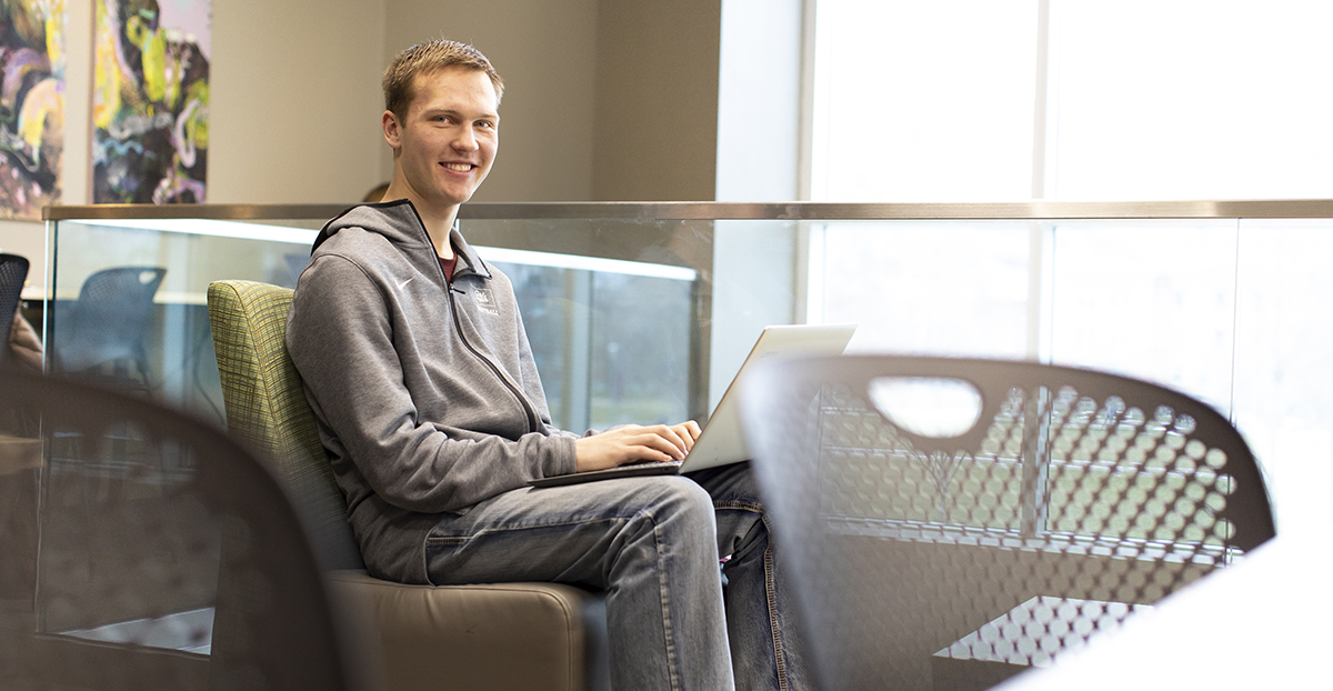 A UM student sits in front of a laptop computer on campus.  