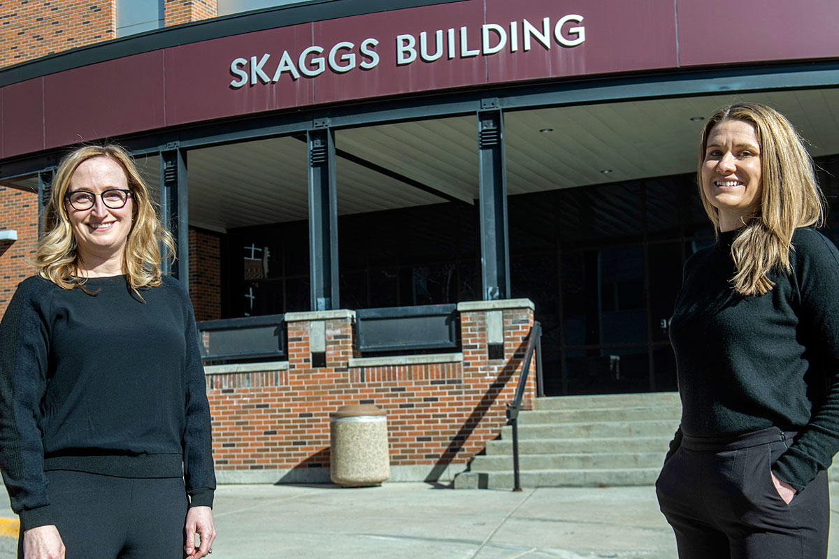 Pharmacy faculty members Erica Woodahl (left) and Hayley Blackburn pose for a picture before UM's Skaggs Building.