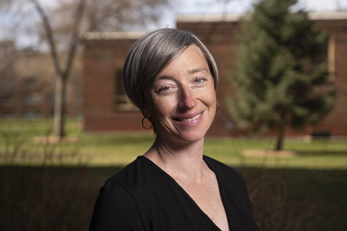 A portrait of a smiling female with short silver hair 