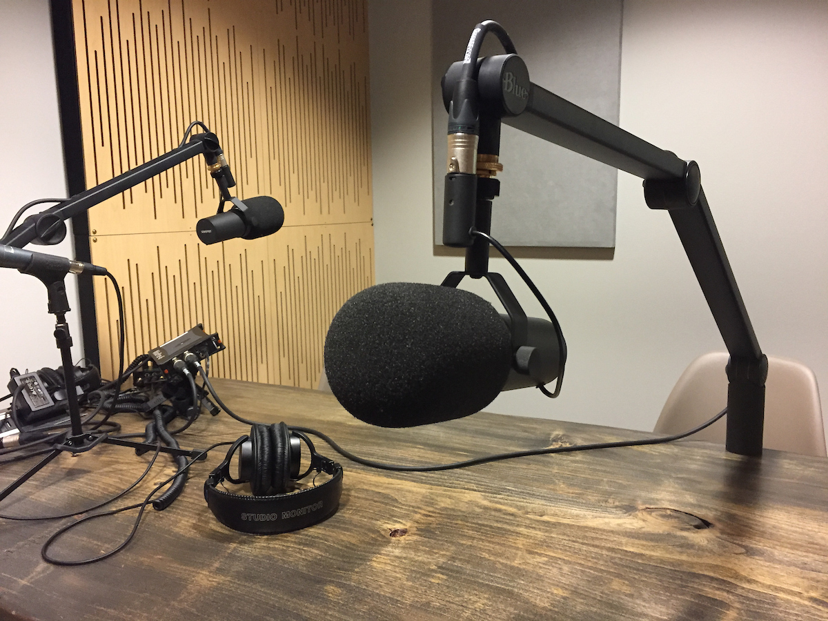 An image of two microphones with headphones and equipment on a desk 