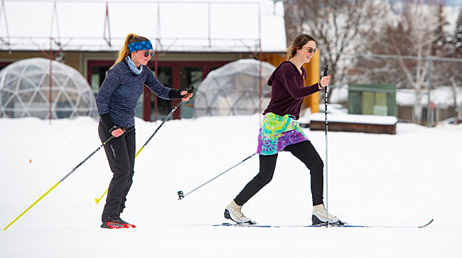 Two female UM students cross-country ski at the UM golf course.