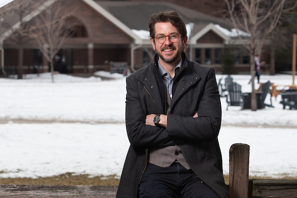eric zimmer leaning on a fence in the snowy UM campus