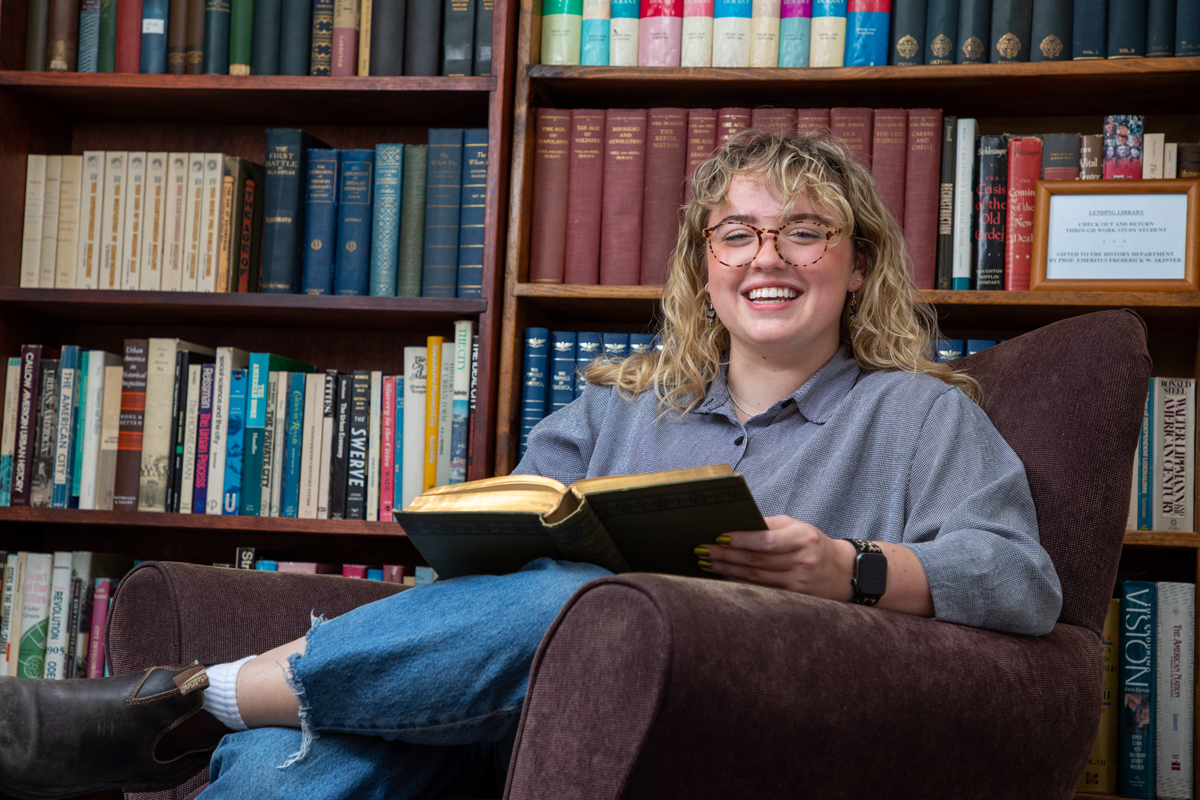 A picture of Maddie Hagan surrounded by books. 