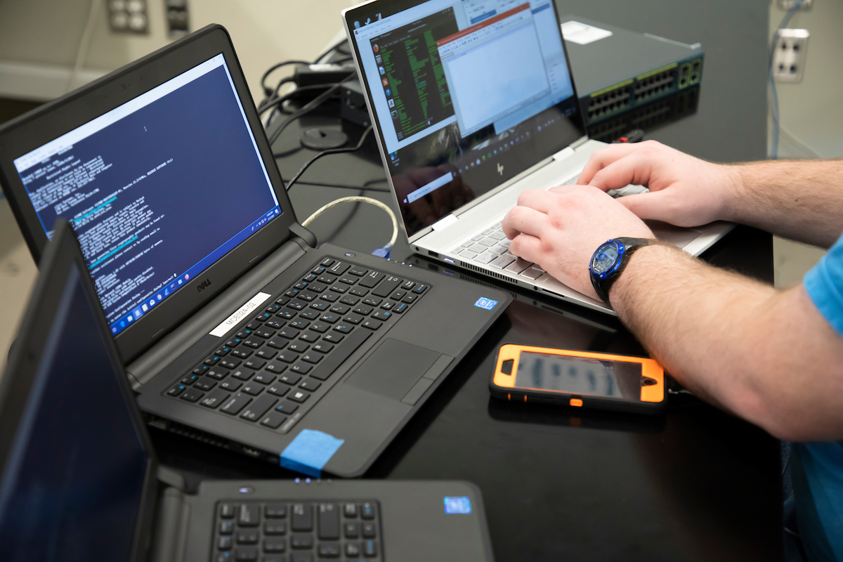Photo of someone sitting at multiple laptops