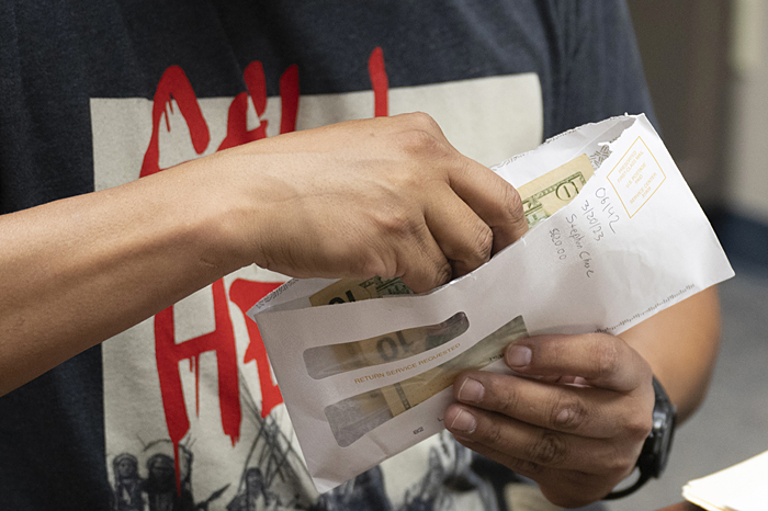 A hand holding and envelope with cash.