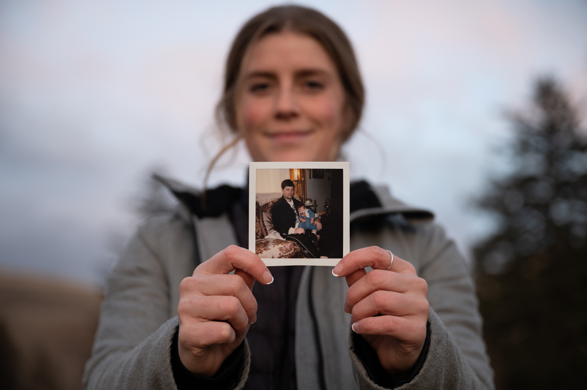 An image of Teigan Avery holding a photo of her father. 