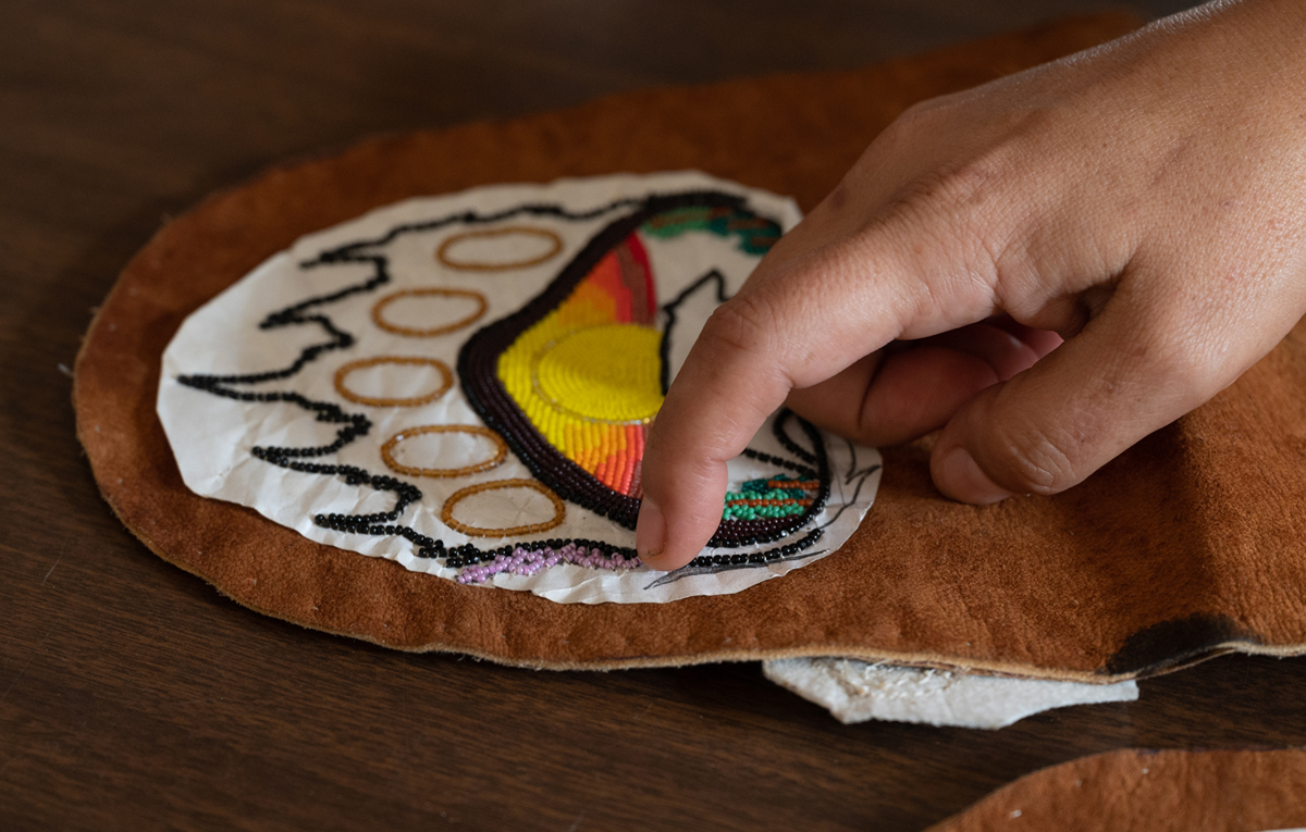An image of a hand touching beadwork.