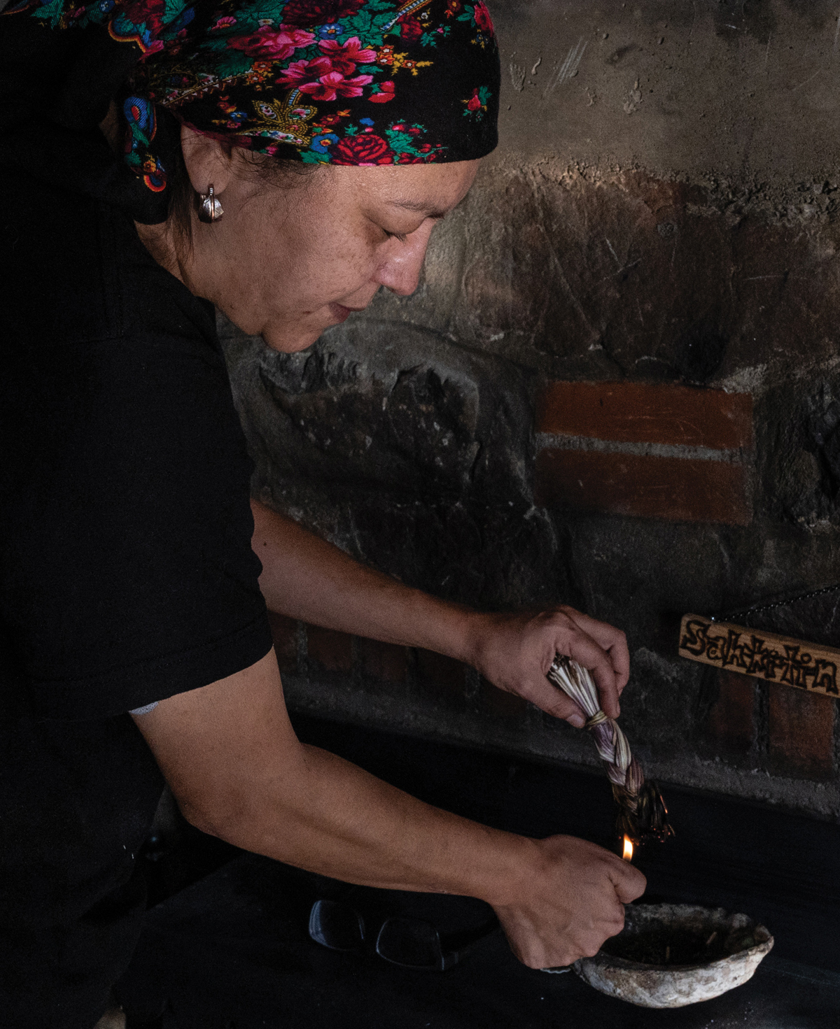 An image of a woman lighting braided sweetgrass on fire. 