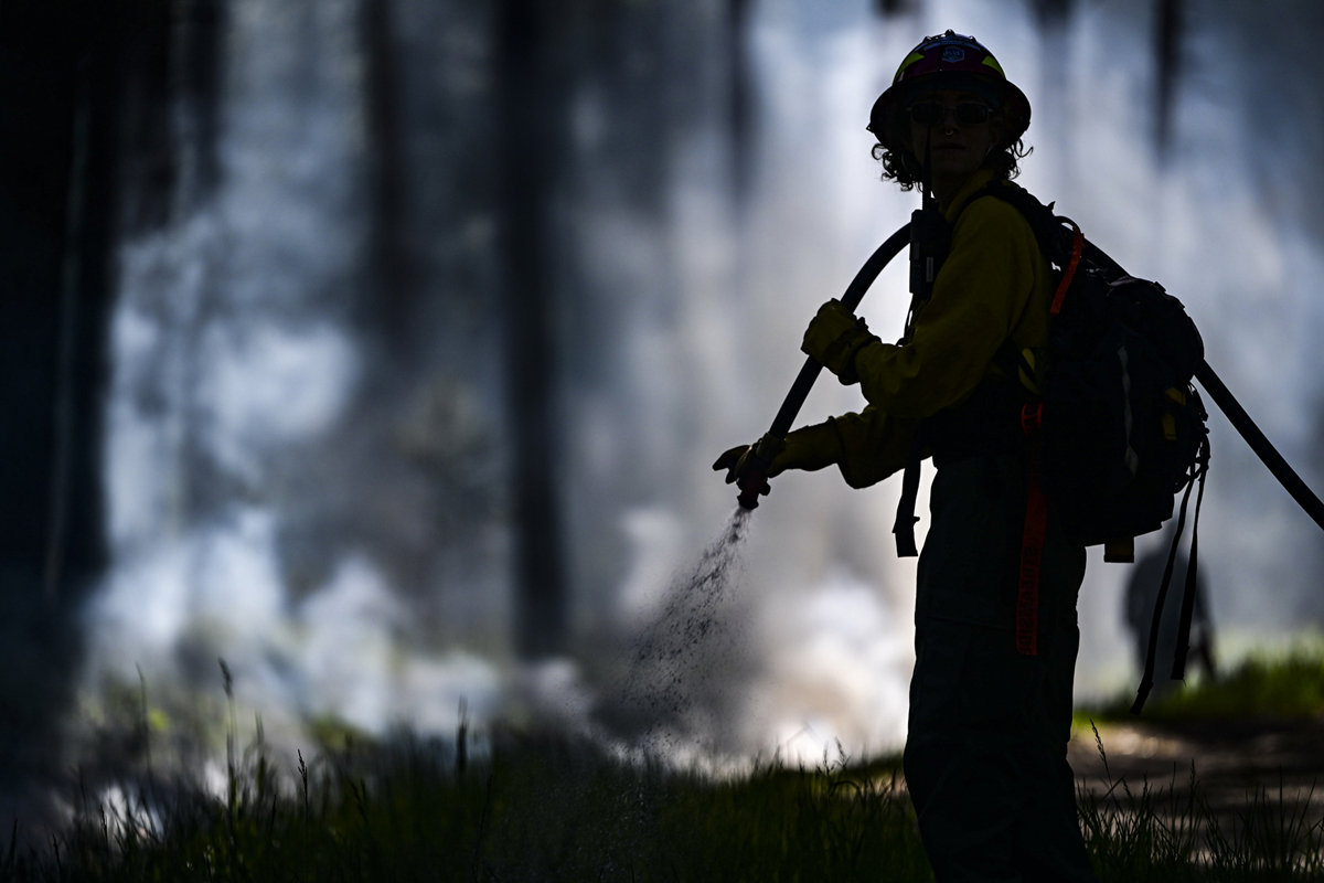 Firefighter deploys water on a wildfire