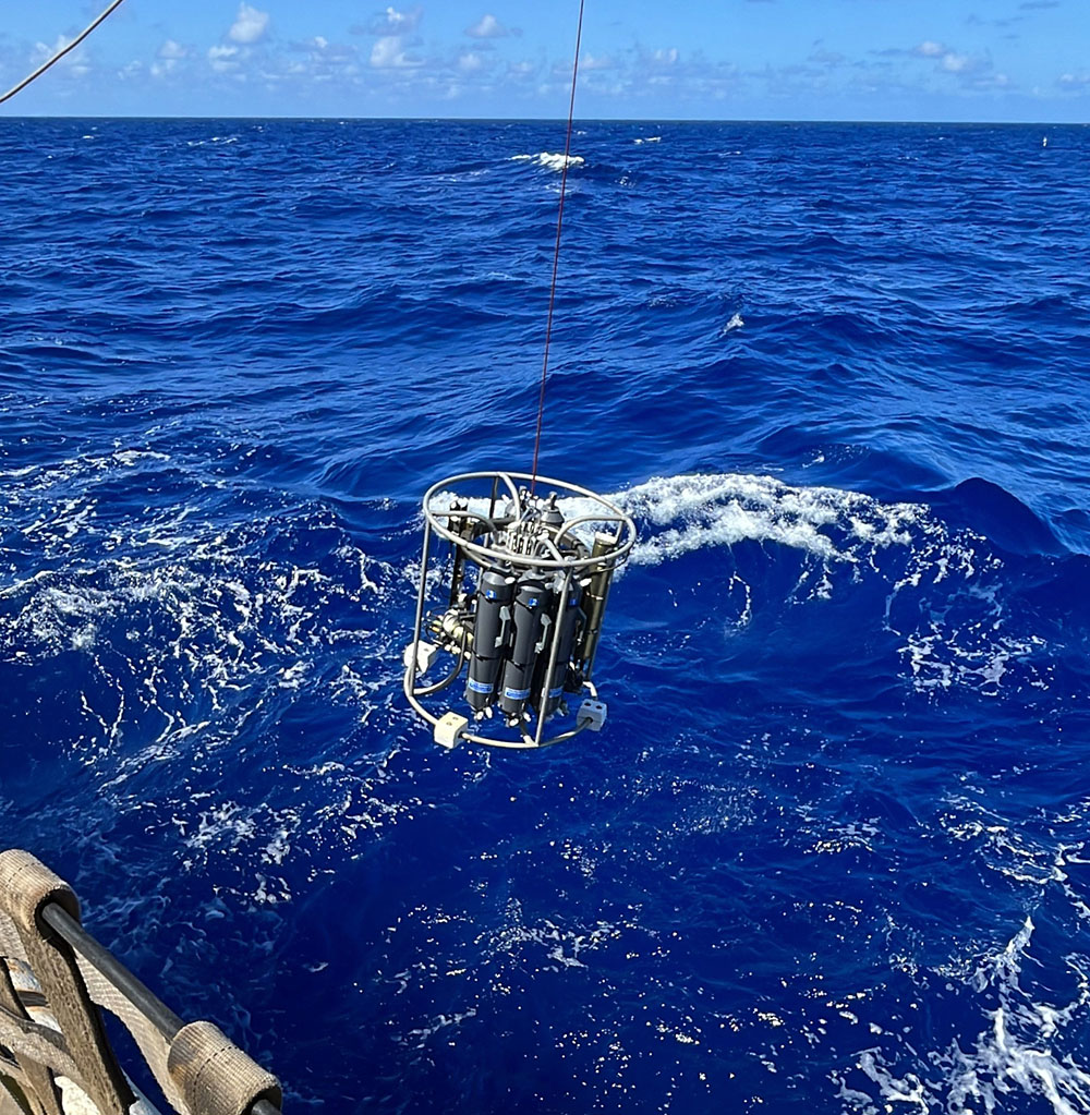 A cylindrical instrument is lowered into the ocean.