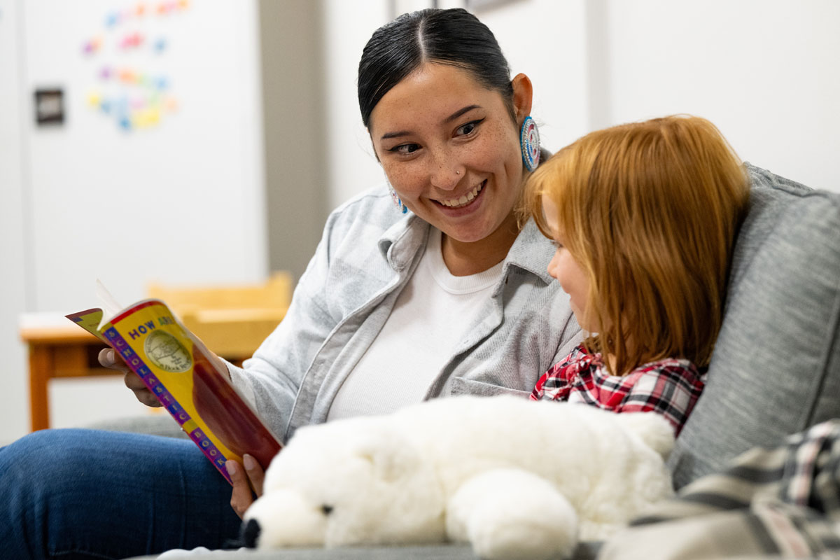 Mikayla Jefferson, a current school psychology student at UM, sits down and reads a book with Kora Fivecoats at the Clinical Psychology Center on the University of Montana campus Wednesday, Oct. 2, 2024. 