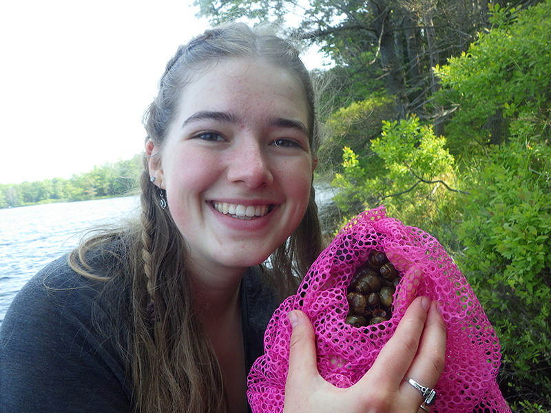 Lauren Western holds the snails she studies on a lakeshore.