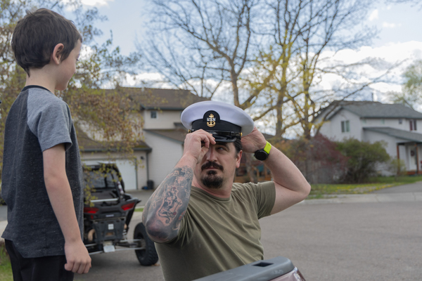 Keely McFarren tries on the hat from his Navy uniform in front of his son
