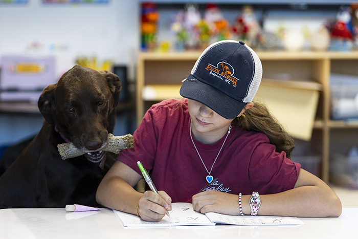 Kenzie Krushensky, 13, writes in her math workbook Sept. 4 alongside Rosie, the teacher’s dog.
