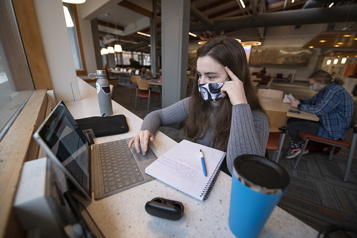 A UM student sits in front of a laptop computer on campus.  