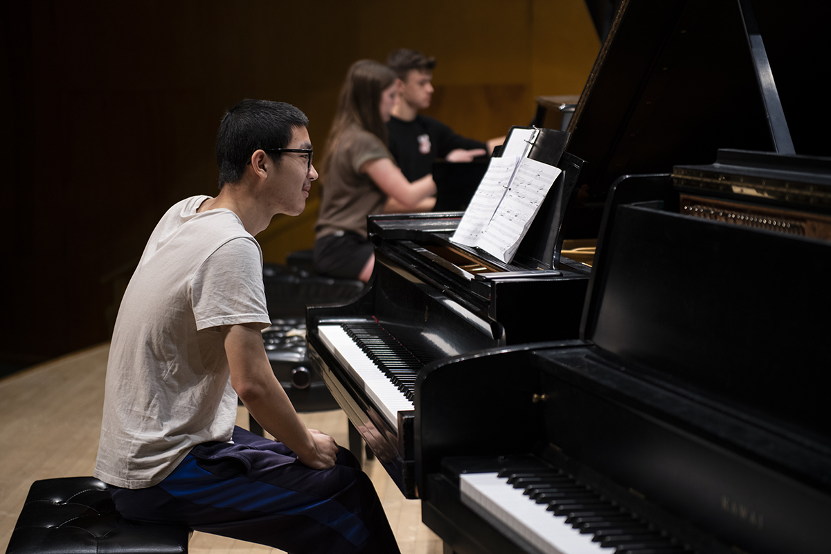 A piano player sits in front of a piano 