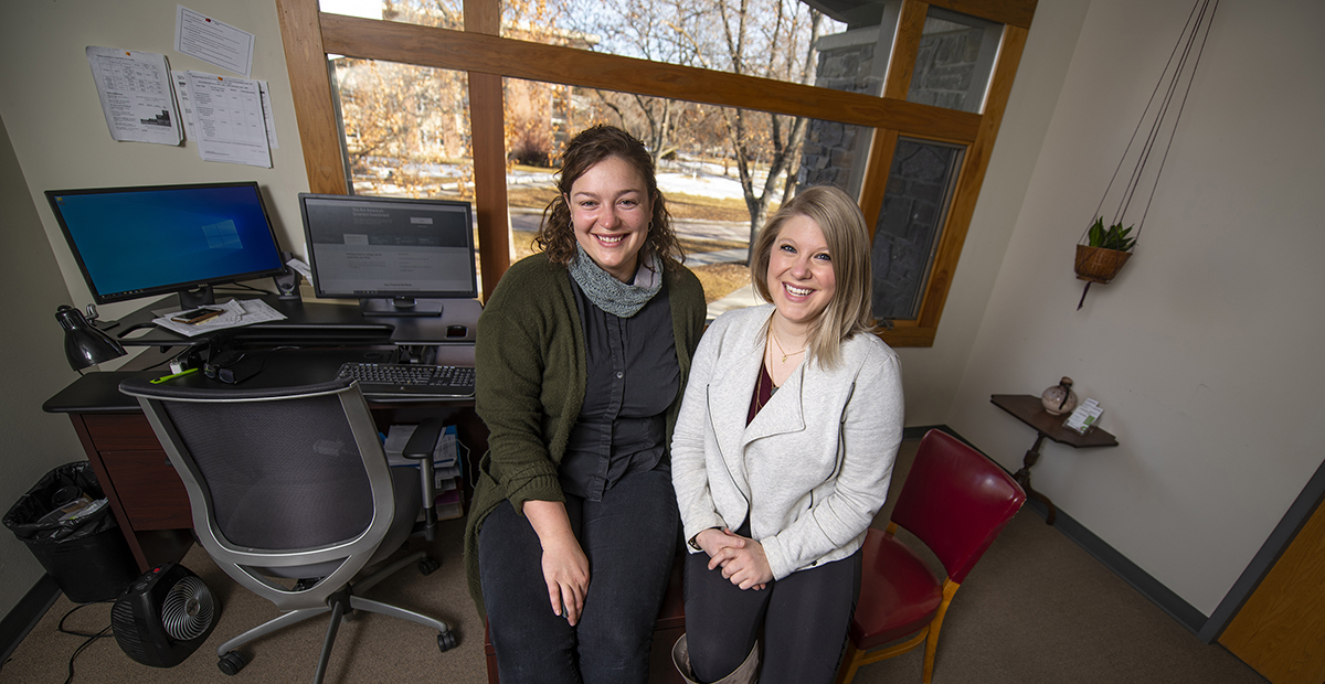 Two female staff members sit in a UM office.