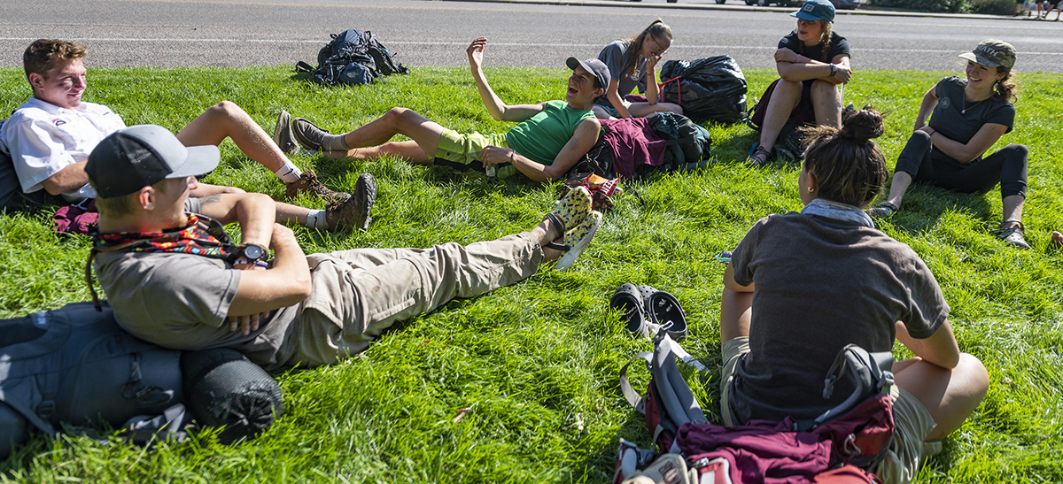 UM students sit on a green law on campus in a circle and talk