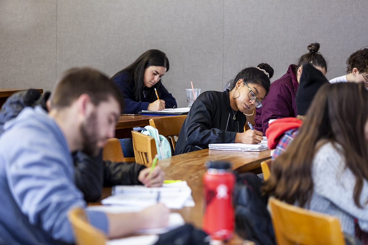 A group of students writes in a notebooks in  classroom. 