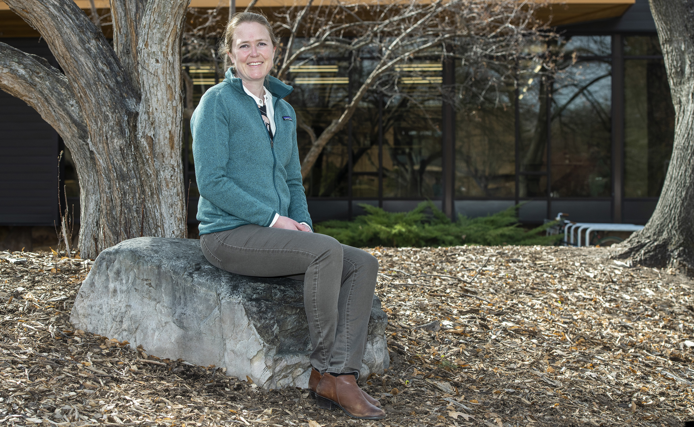 Hilary Martens, in a blue sweatshirt, sits on a rock 