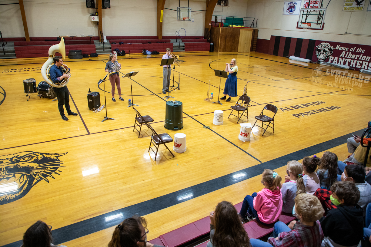 UM music alumni play instruments in a school gymnasium 