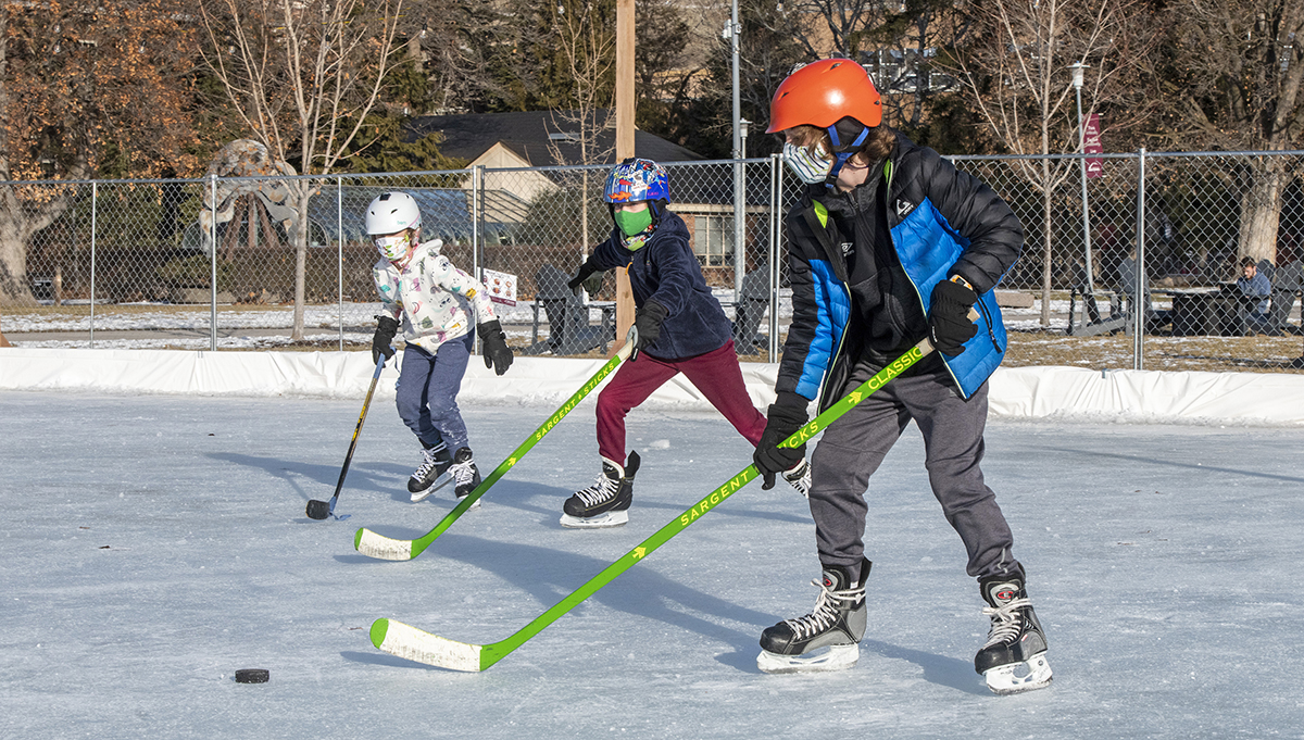 Three children skate on the ice rink on the UM Oval. 