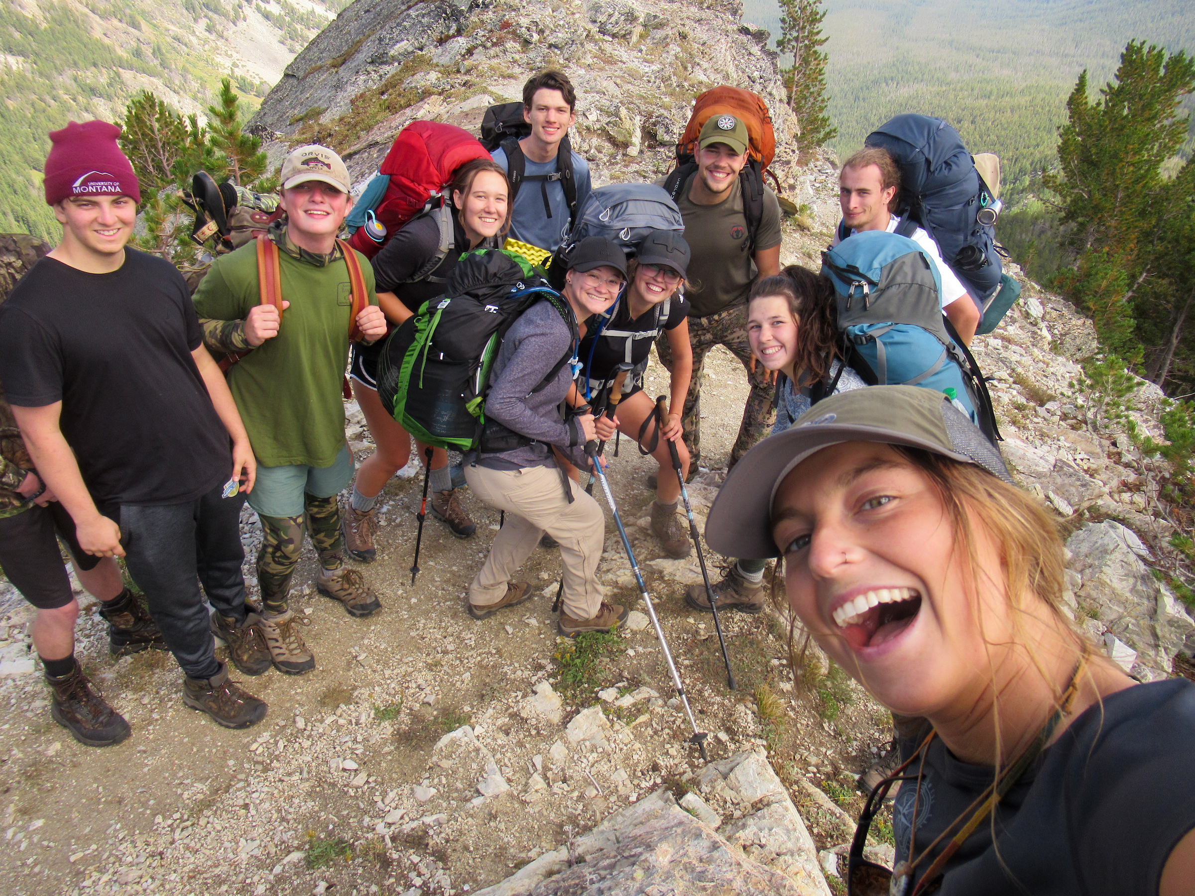 Students gathered on a mountain summit give a thumbs up 