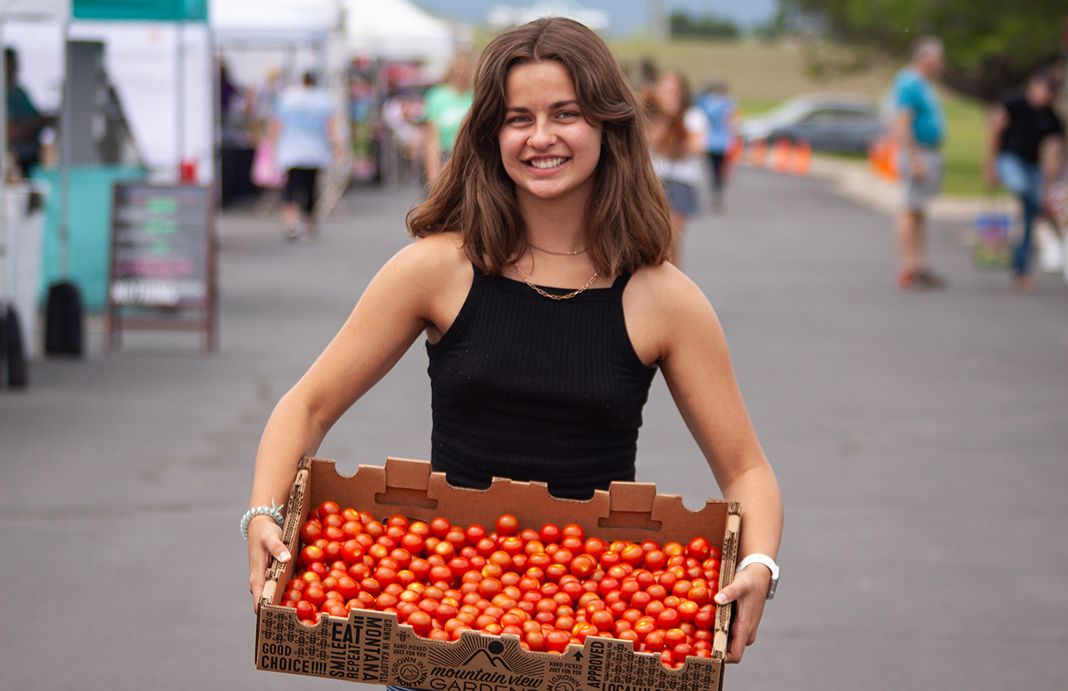 A girl holding a basket of tomatoes