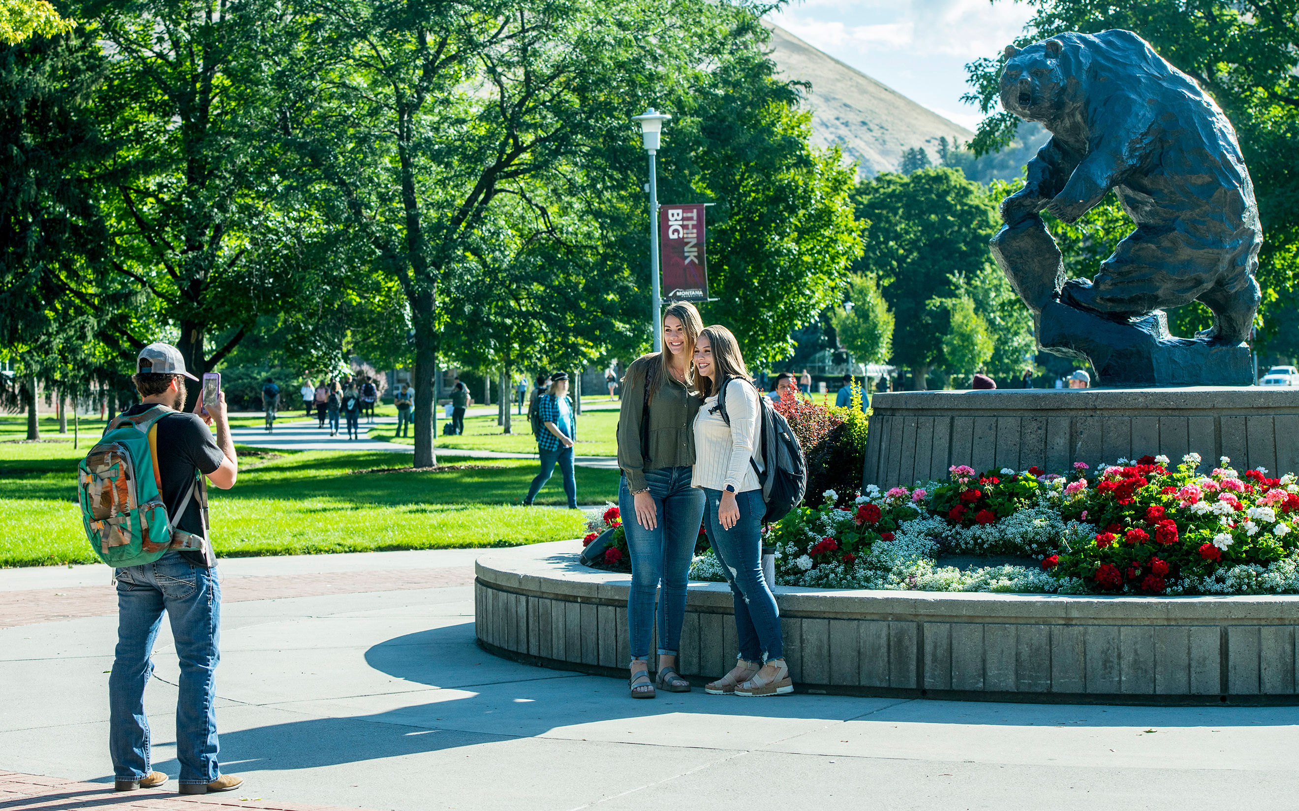 Students take a photo in front of the Grizzly bear Statue