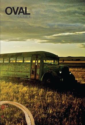 Weathered green bus in a grassy field at sunset under a cloudy sky, with the title “OVAL” in the top left.