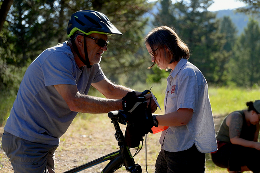 Student interviewing mountain biker out on the trail