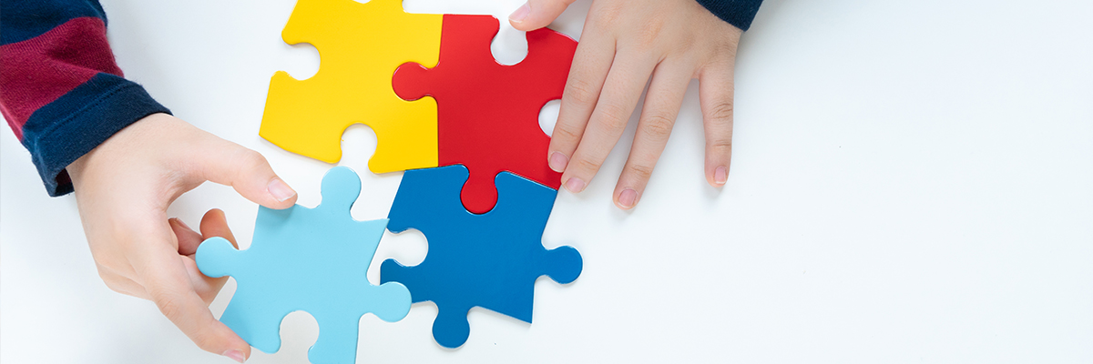 Top view hands of a little child arranging color puzzle symbol of public awareness for autism spectrum disorder