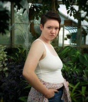 Michelle Williams standing amongst many green plants.