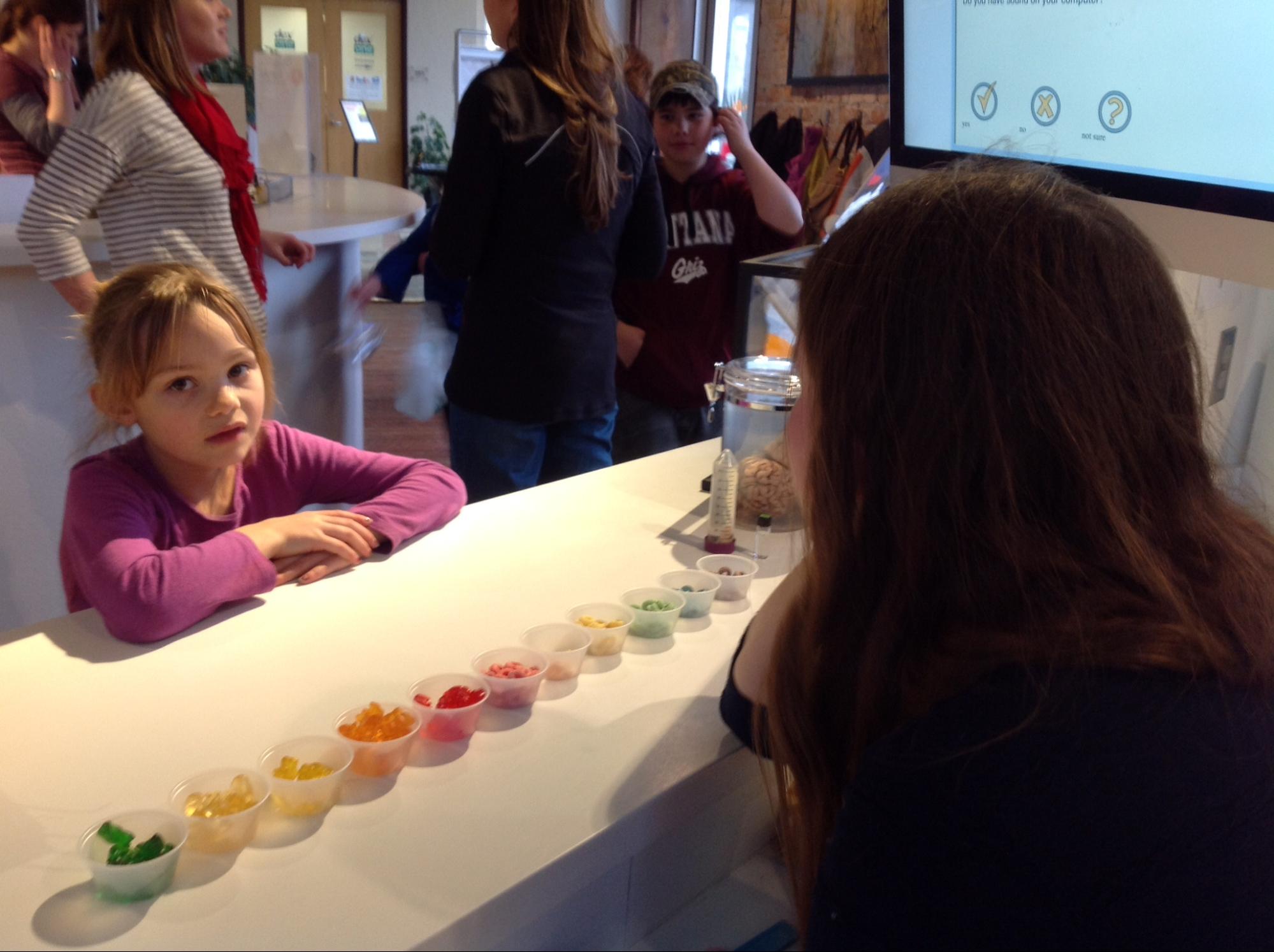 child doing perception taste test at the BrainLab with colled educator during our First Friday event.