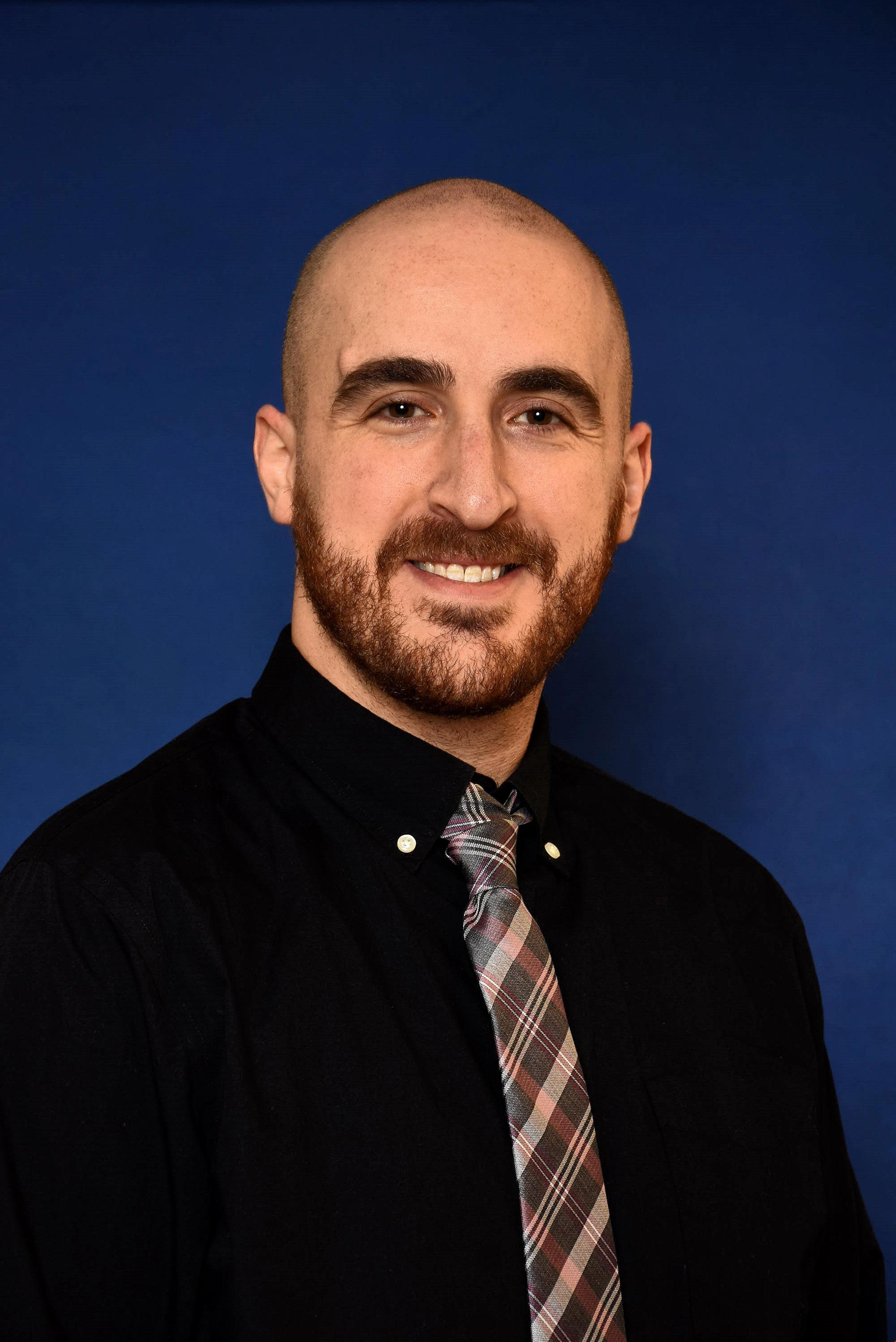 man in a black shirt with checkered tie, blue background