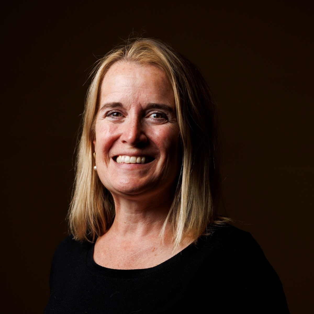 woman smiling dressed in black with black background
