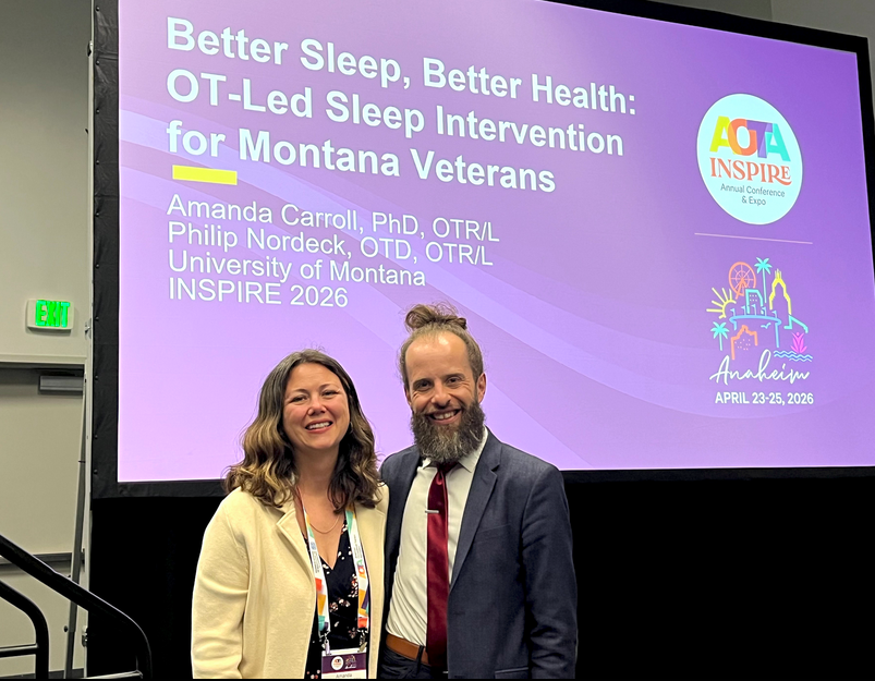 a photo of doctor amanda carroll and doctor philip nordeck at national conference in front of powerpoint presentation screen