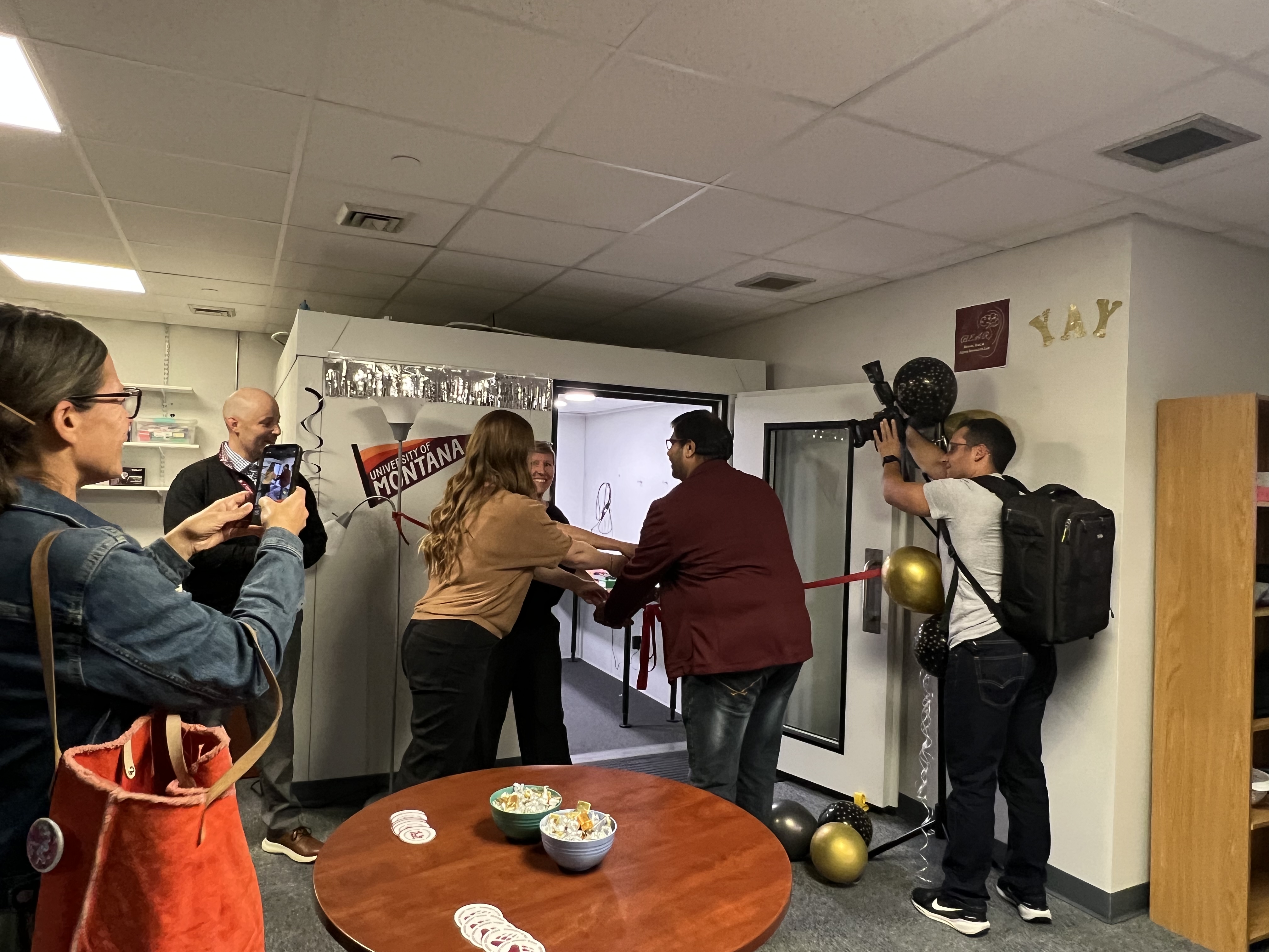 people cutting the ribbon in front of an audiology booth