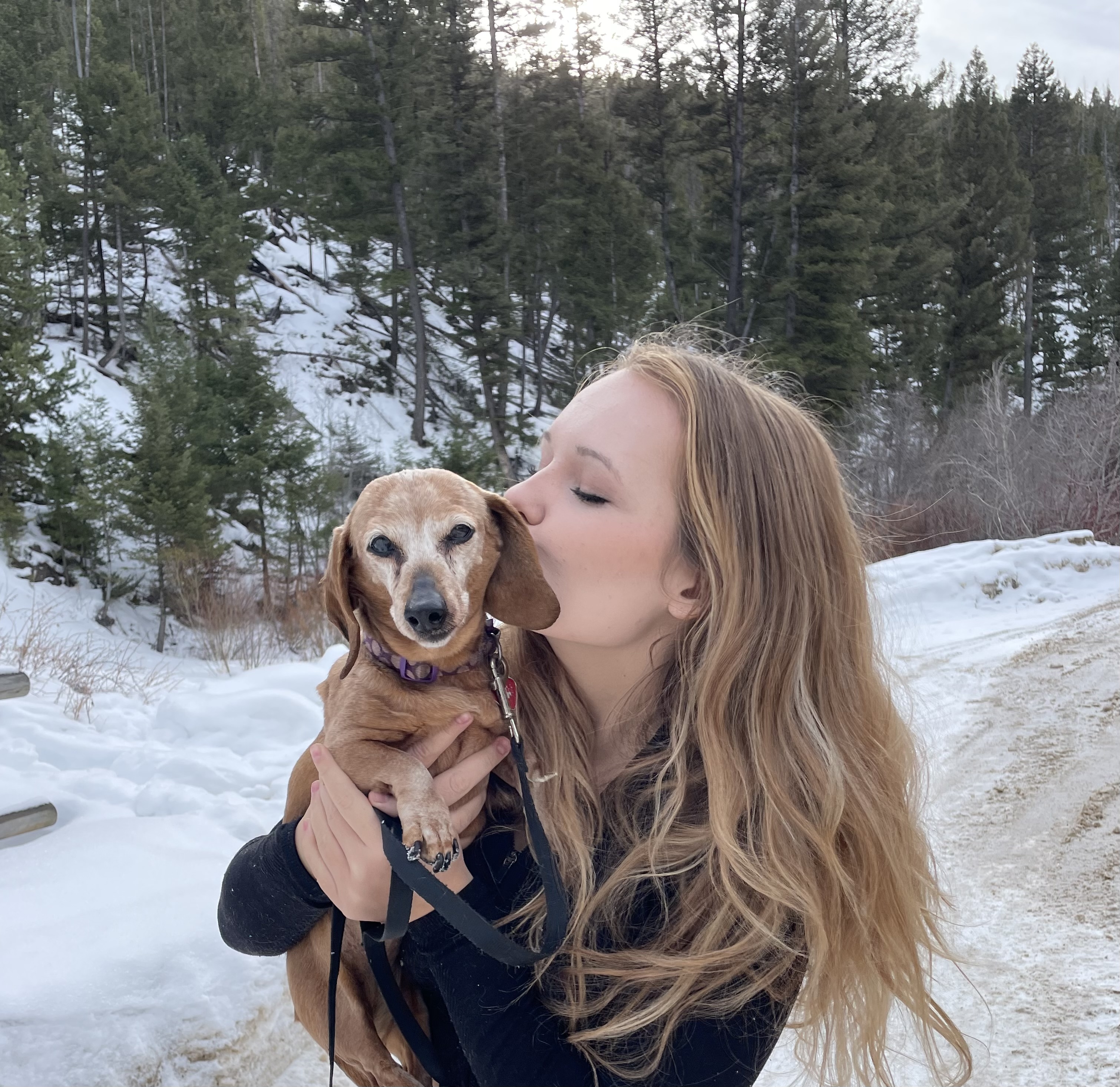 Maisie giving her dog, Auggie, a kiss. 