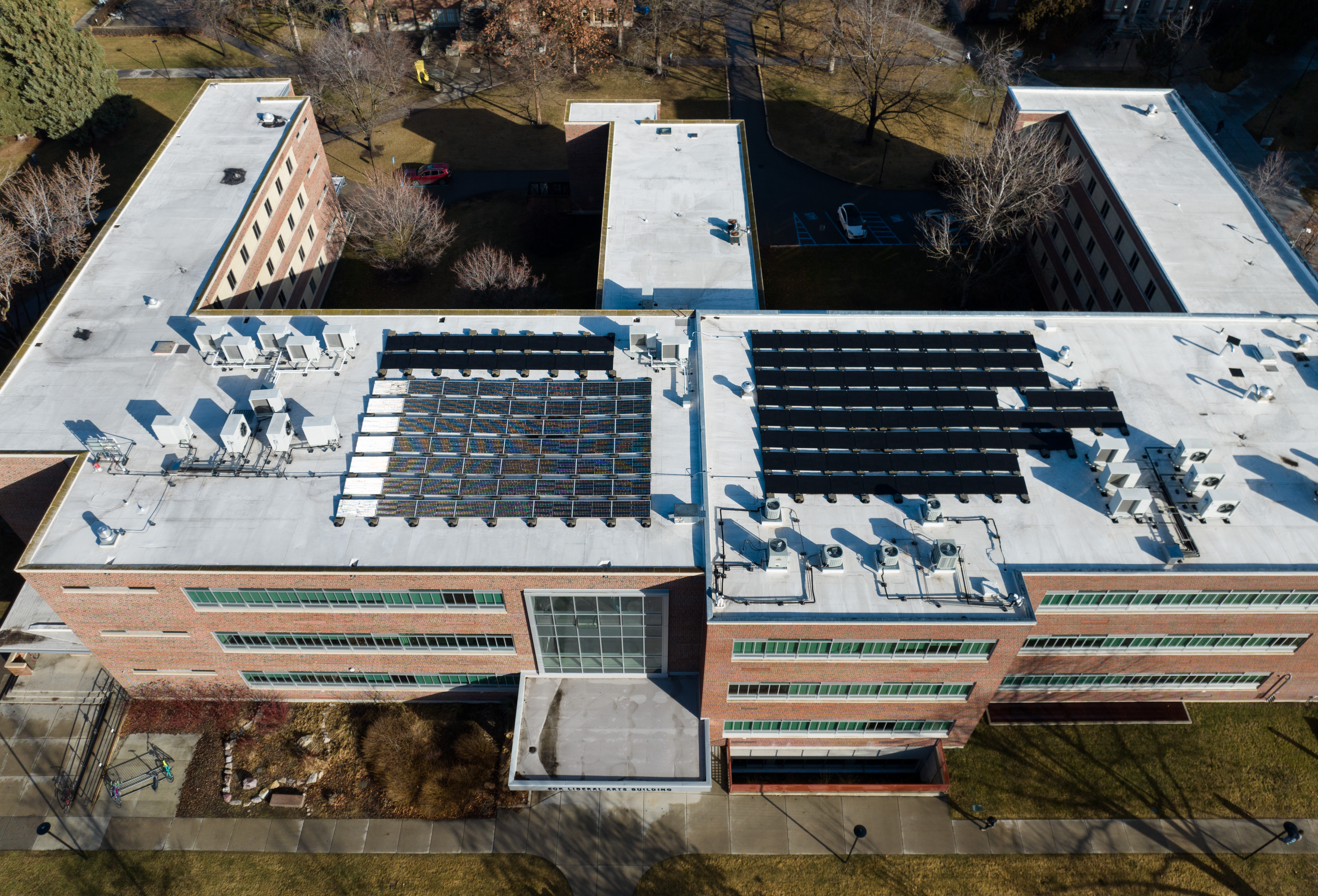 Aerial view of a brick campus building with rooftop solar panels and HVAC equipment.