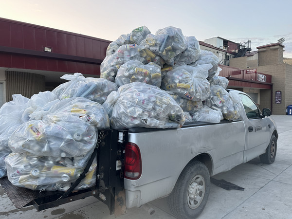 A pickup truck overflowing with large bags of cans in Griz Stadium.