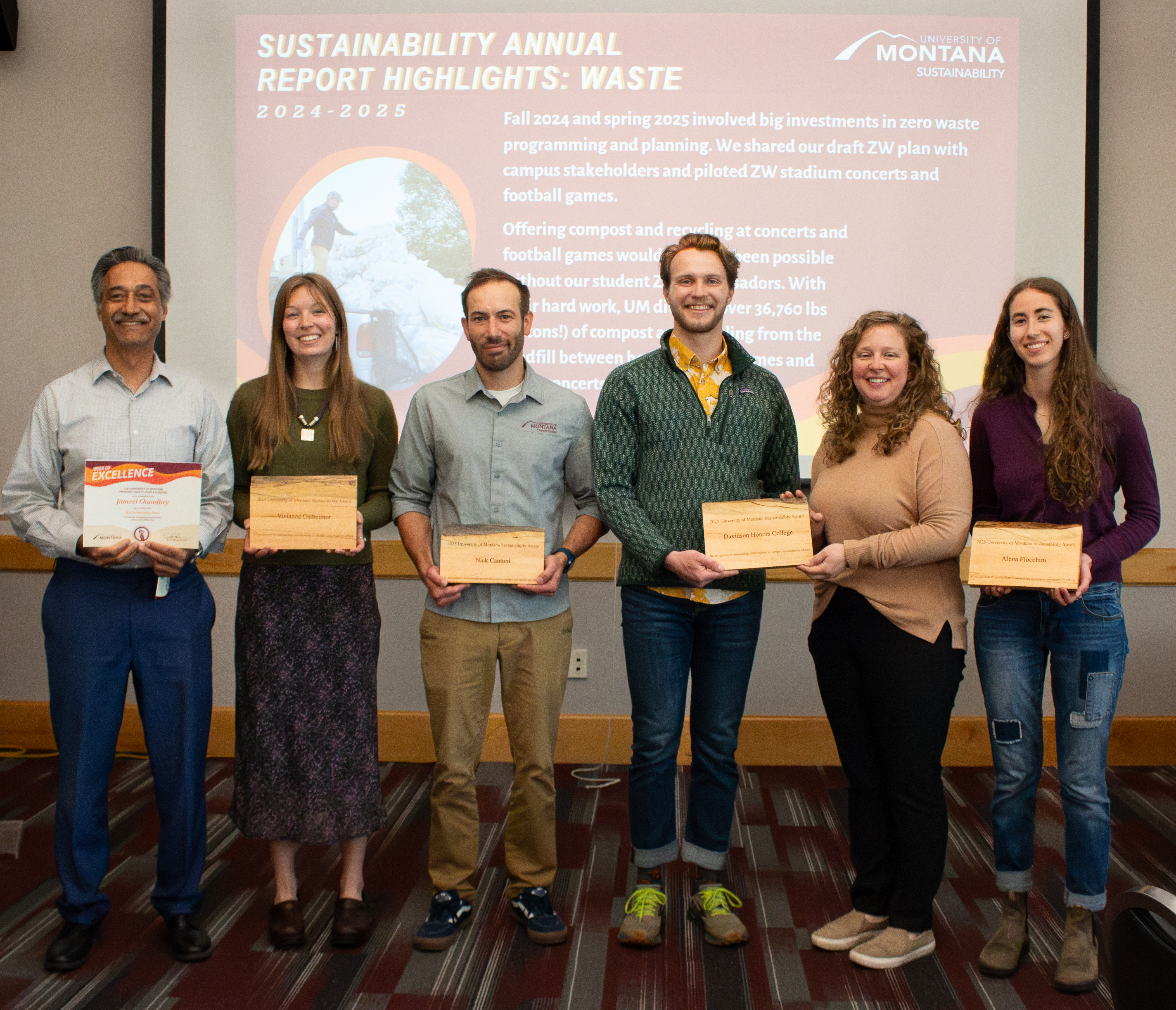 Six sustainability award recipients stand together holding plaques. 