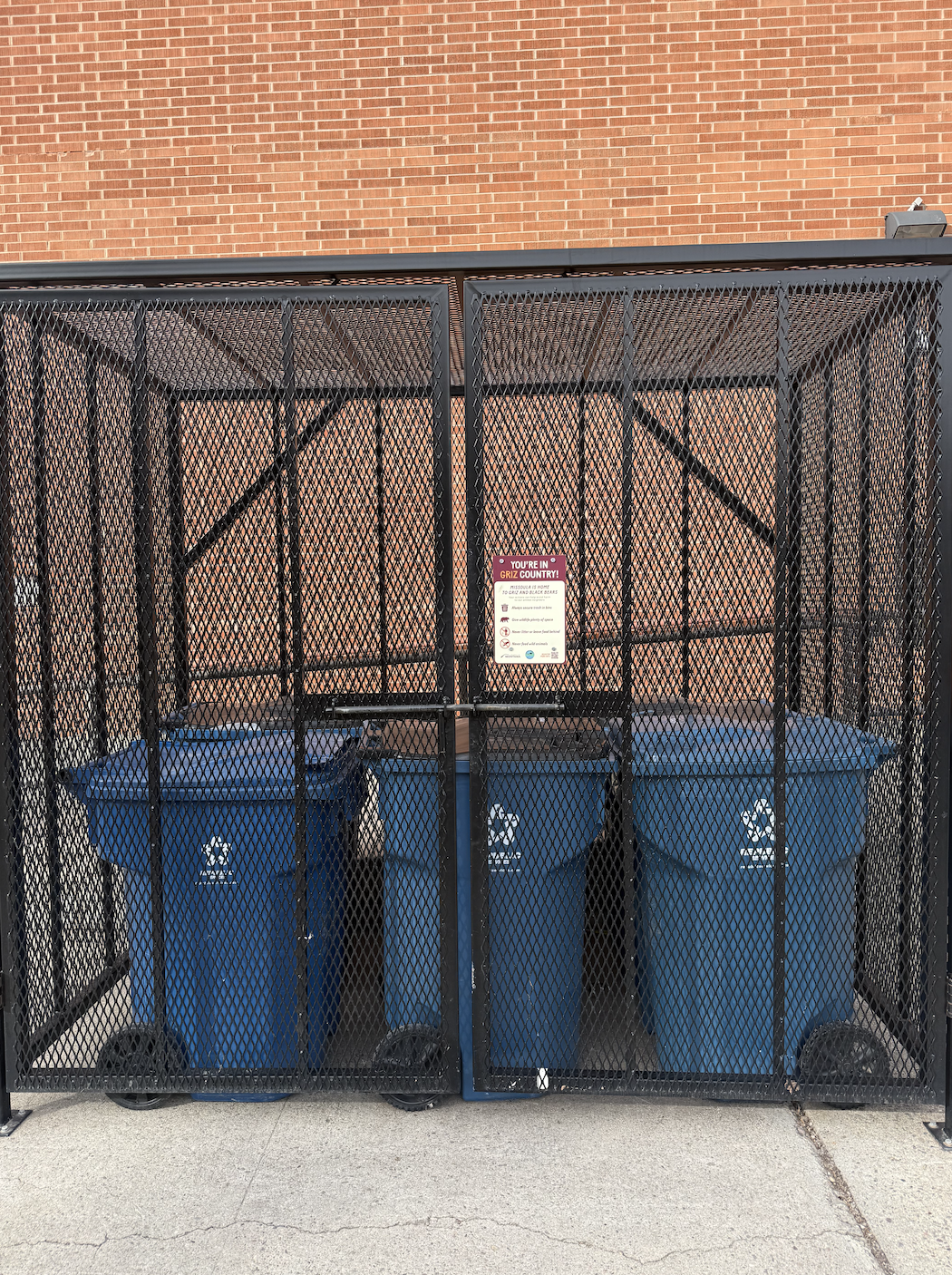 metal corral around blue trash bins at aber hall
