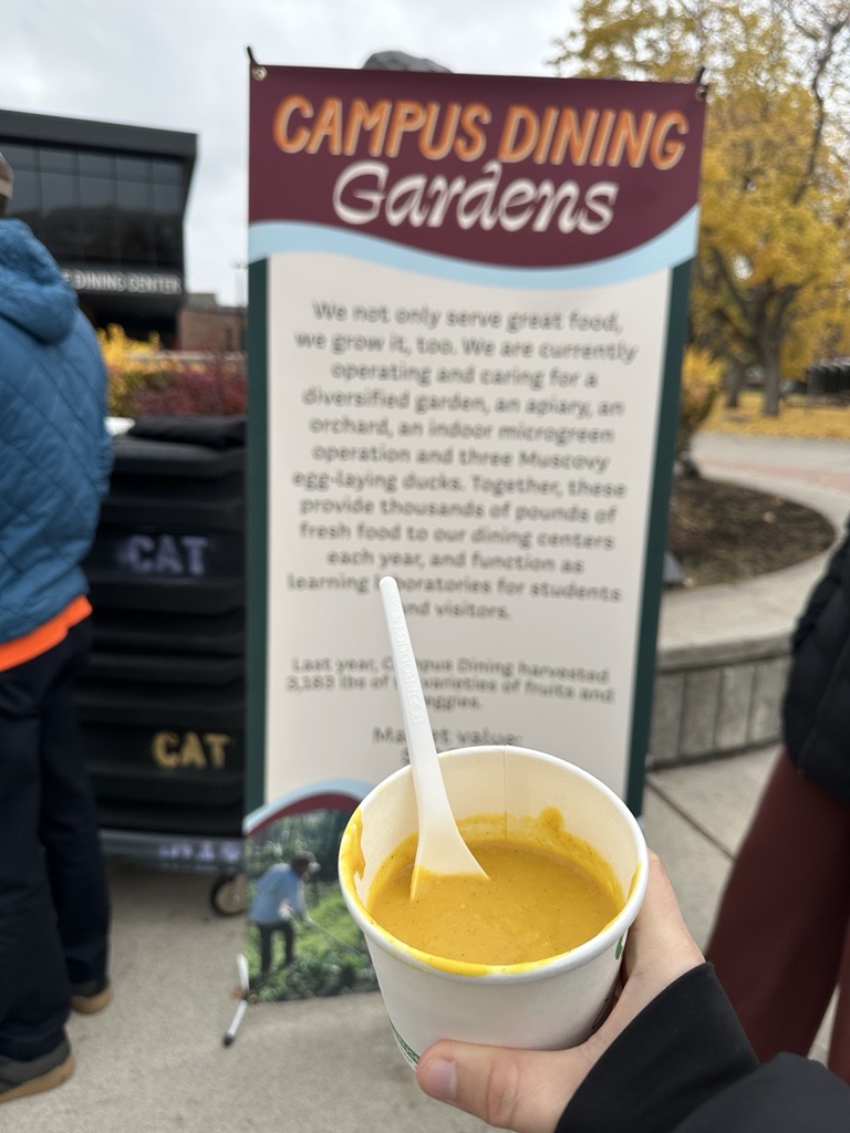 cup of soup in front of a blurred campus dining sign
